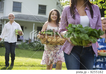 Family Party. Parents And Children Walking Across The Lawn Carrying Flowers, Fresh Picked Vegetables And Fruits. Preparing For A Party. 9255162