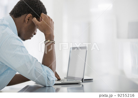 Office Interior. A Man Seated At A Table, Using A Laptop Computer. Office Interior. A Man Seated At A Table, Using A Laptop Computer. 9255216