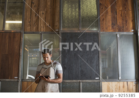 A Young Man In A Workshop. Using A Digital Tablet To Keep Records And Photograph Objects. A Young Man In A Workshop. Using A Digital Tablet To Keep Records And Photograph Objects. 9255385