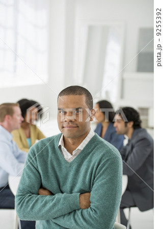 Business Meeting. A Group Sitting Down Around A Table. A Man Smiling Confidently. Business Meeting. A Group Sitting Down Around A Table. A Man Smiling Confidently. 9255392