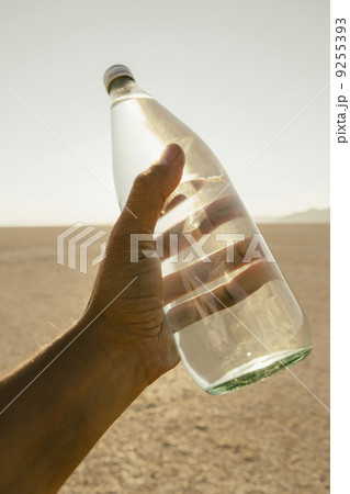 The Landscape Of The Black Rock Desert In Nevada. A Man'S Hand Holding A Bottle Of Water. Filtered Mineral Water. The Landscape Of The Black Rock Desert In Nevada. A Man'S Hand Holding A Bottle Of Water. Filtered Mineral Water. 9255393