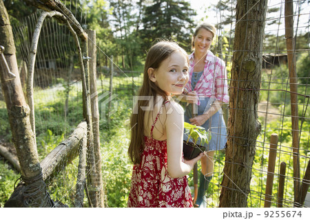 A Woman And A Child Holding A Young Green Plant In A Pot. A Woman And A Child Holding A Young Green Plant In A Pot. 9255674