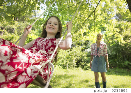 Summer. A Girl In A Sundress On A Swing Under A Leafy Tree. A Woman Standing Behind Her. Summer. A Girl In A Sundress On A Swing Under A Leafy Tree. A Woman Standing Behind Her. 9255692