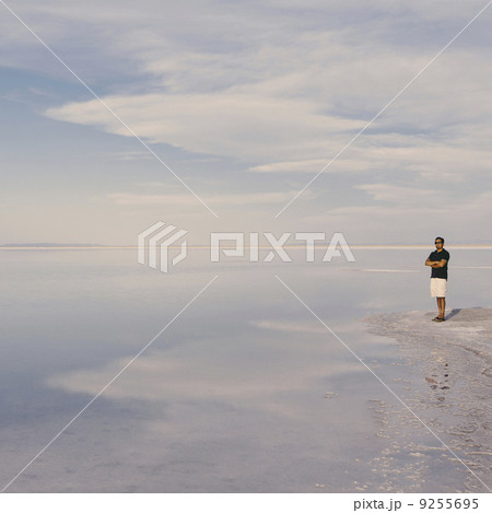 A Man Standing At Edge Of The Flooded Bonneville Salt Flats At Dusk. Arms Folded.  9255695