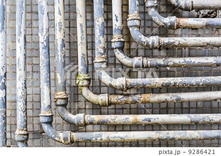 Series of parallel old pipes on wall 9286421