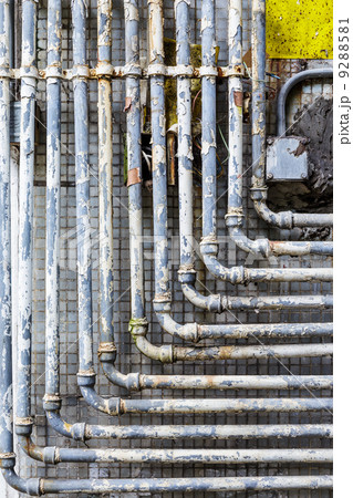 Series of parallel old pipes on wall 9288581