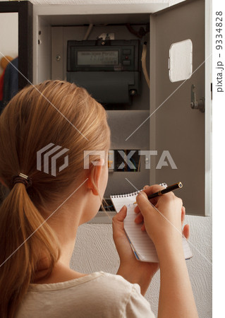 Young woman rewrites the electrical meter readings Young woman rewrites the electrical meter readings 9334828