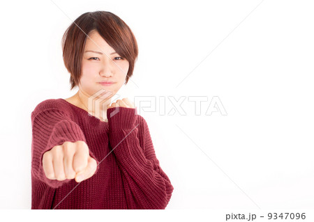可愛らしく怒った表情でパンチをするショートヘアの女の子 9347096