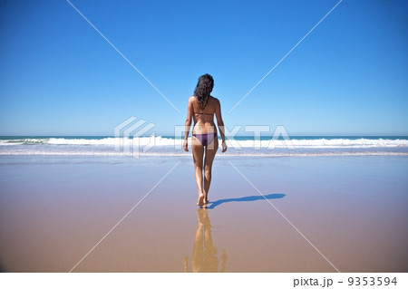 woman walking towards water at seashore 9353594