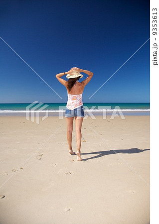 holding on straw hat at beach 9353613