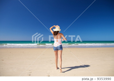 walking holding on straw hat at beach 9353990