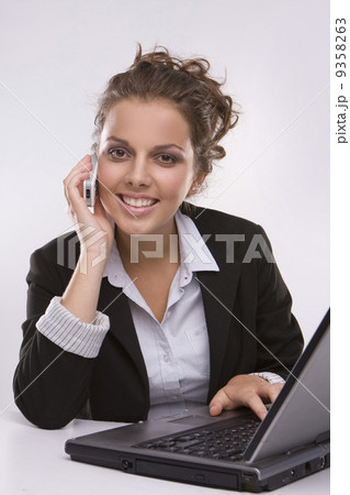 woman using a laptop computer and talking on the phone woman using a laptop computer and talking on the phone 9358263