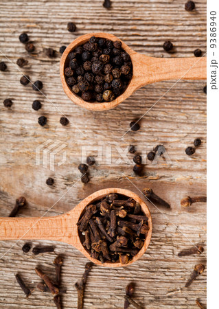 black pepper and cloves in wooden spoons black pepper and cloves in wooden spoons 9386940