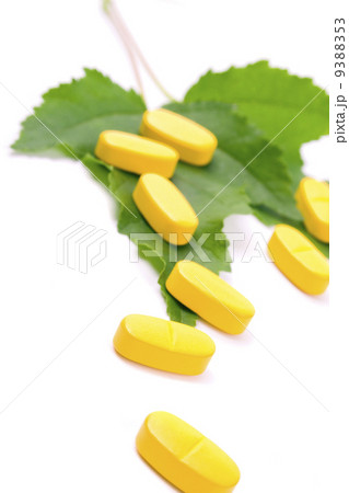 yellow vitamin pills over green leaves 9388353