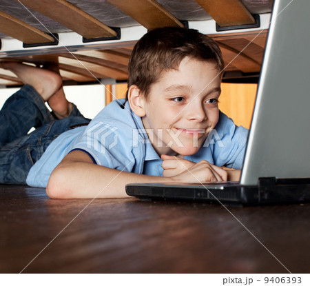 Child playing laptop under the bed Child playing laptop under the bed 9406393