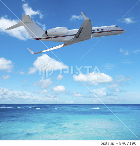 Private jet plane over the tropical sea 9407190