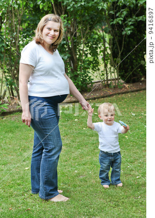 Young pregnant woman and little son in summer garden 9416897