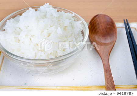 White steamed rice in bowl with chopsticks and wood spoon . 9419787