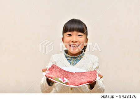 すき焼きの肉を差し出す女の子 9423176