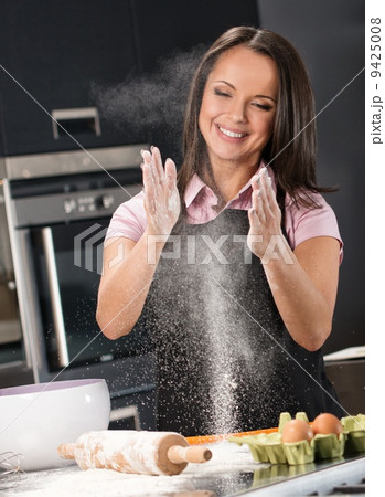 Young woman having fun with flour while making dough on a modern kitchen Young woman having fun with flour while making dough on a modern kitchen 9425008