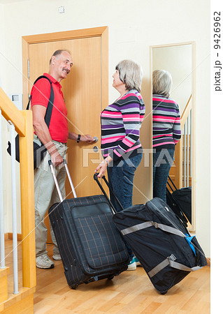 Mature couple with suitcases near door Mature couple with suitcases near door 9426962