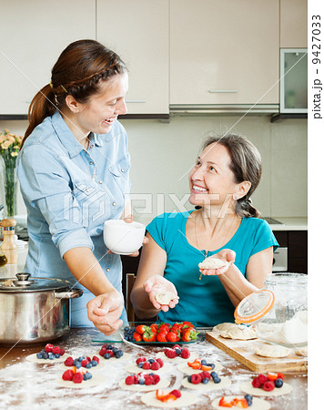 Happy mother with daughter making berries dumplings 9427033