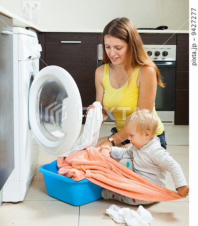 Family woman putting clothes in to washing machine 9427277