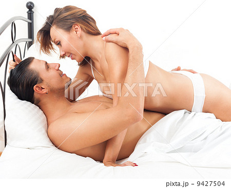 Smiling adult couple having sex on bed in bedroom interior 9427504