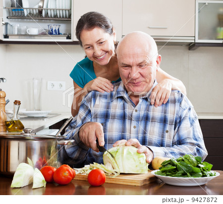 Joyful mature couple cooking food Joyful mature couple cooking food 9427872