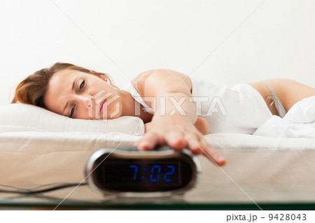 Tired red-haired young woman in the morning switching off the al Tired red-haired young woman in the morning switching off the al 9428043