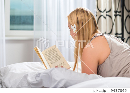 Young woman in Hotel reading book in bed 9437046