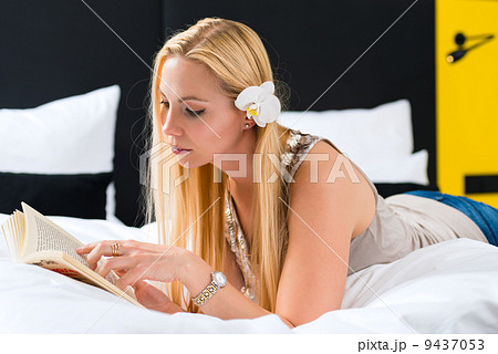 Young woman in Hotel reading book in bed 9437053