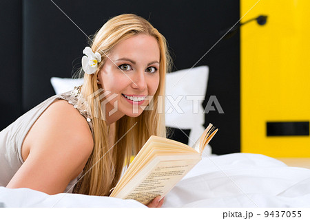 Young woman in Hotel reading book in bed 9437055