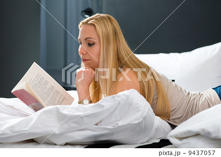 Young woman in Hotel reading book in bed 9437057
