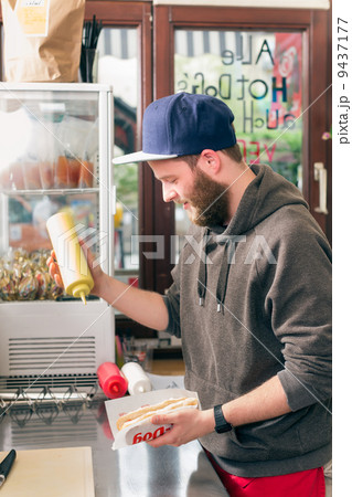 salesman making hotdog in fast food snack bar 9437177