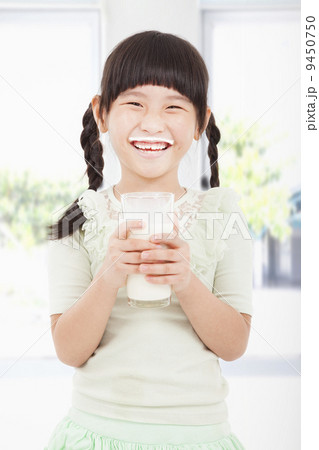 Happy little girl holding a glass of fresh milk Happy little girl holding a glass of fresh milk 9450750