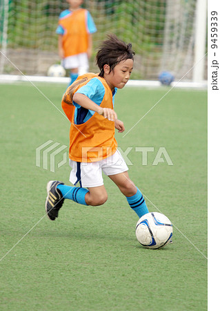 ユニフォームを着たサッカー少年のドリブルシーンの写真素材