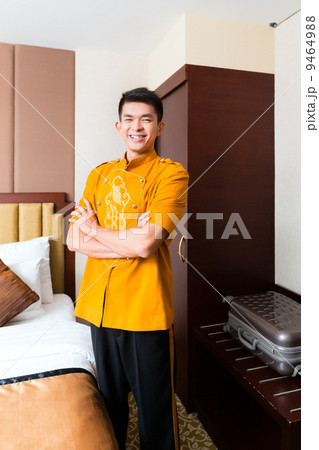 Asian Chinese porter bringing suitcase to luxury hotel room 9464988