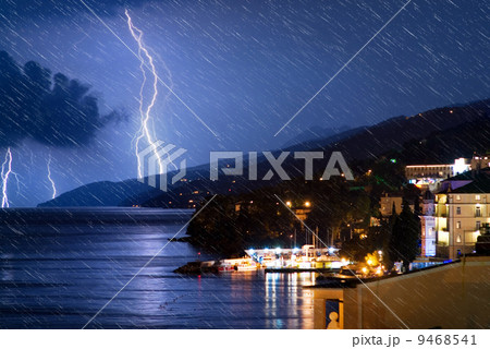 Small city near the ocean at stormy night (with realistic rain e 9468541