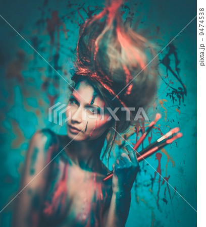 Young woman muse with creative body art and hairdo holding paint brushes Young woman muse with creative body art and hairdo holding paint brushes 9474538