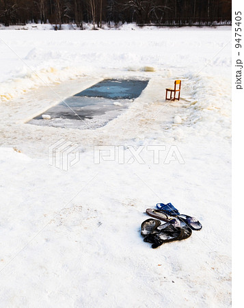 slippers and chair near ice hole in frozen lake 9475405