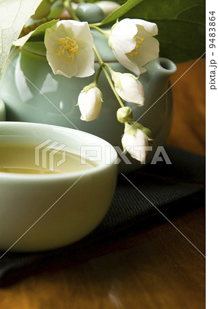 Green tea with jasmine in cup and teapot on wooden table Green tea with jasmine in cup and teapot on wooden table 9483864