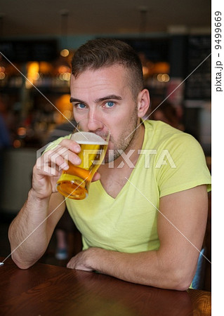Handsome young man drinking light beer in a pub Handsome young man drinking light beer in a pub 9499669