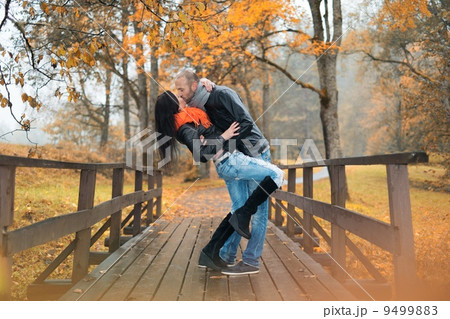 Happy middle-aged couple kissing outdoors on beautiful autumn day 9499883