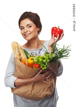 Smiling brunette woman with grocery bag full of fresh vegetables and red paprika 9499884