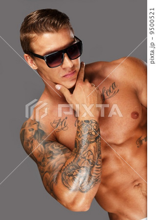 Handsome man in sunglasses with muscular tattooed torso 9500521