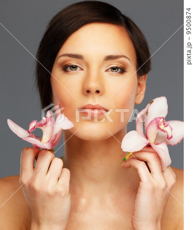 Young beautiful brunette woman with orchid flowers Young beautiful brunette woman with orchid flowers 9500874