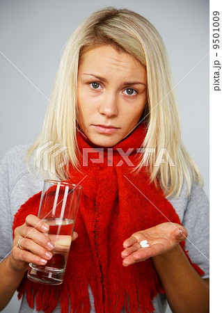 Sick young blond woman with pills and glass of water Sick young blond woman with pills and glass of water 9501009
