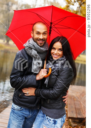 Happy middle-aged couple with umbrella outdoors on beautiful rainy autumn day 9501296