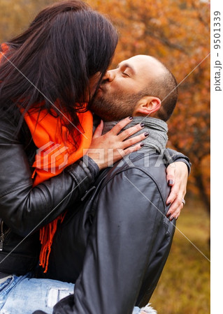 Happy middle-aged couple kissing outdoors on beautiful autumn day 9501339